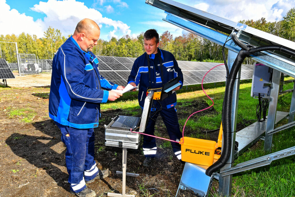 Zwei Mitarbeiter der Stromversorgung arbeiten an einer Photovoltaikanlage