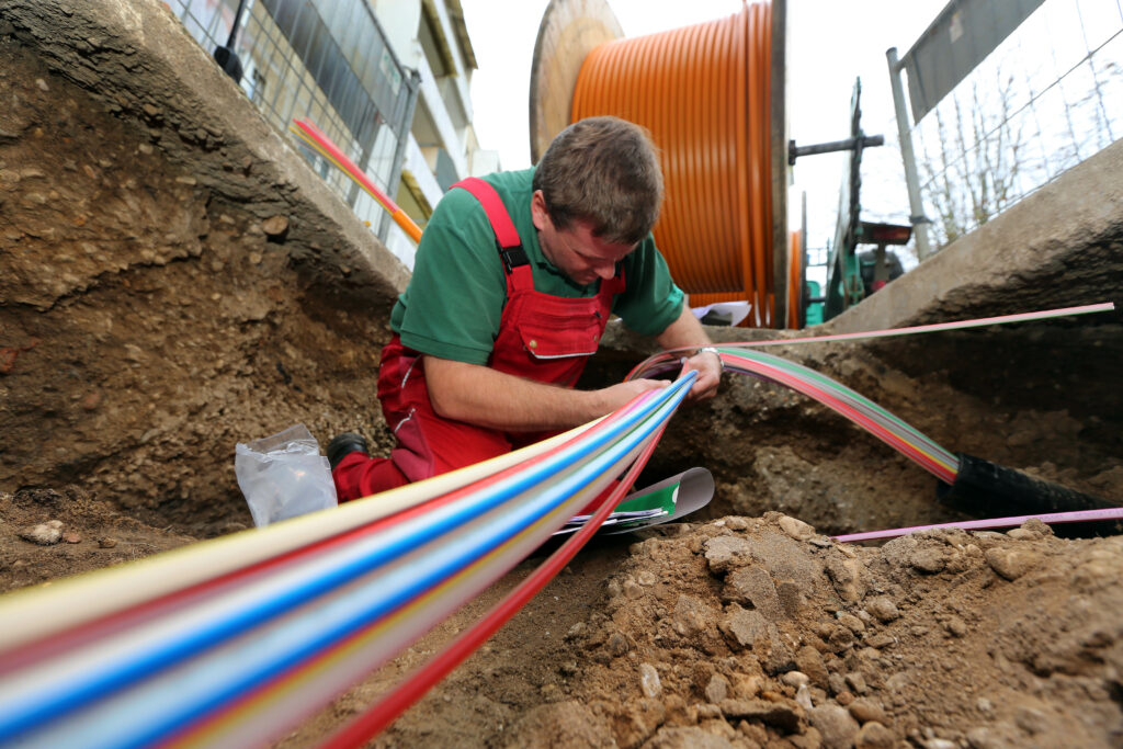 Eine Person verlegt Glasfaserkabel in einer Baustelle