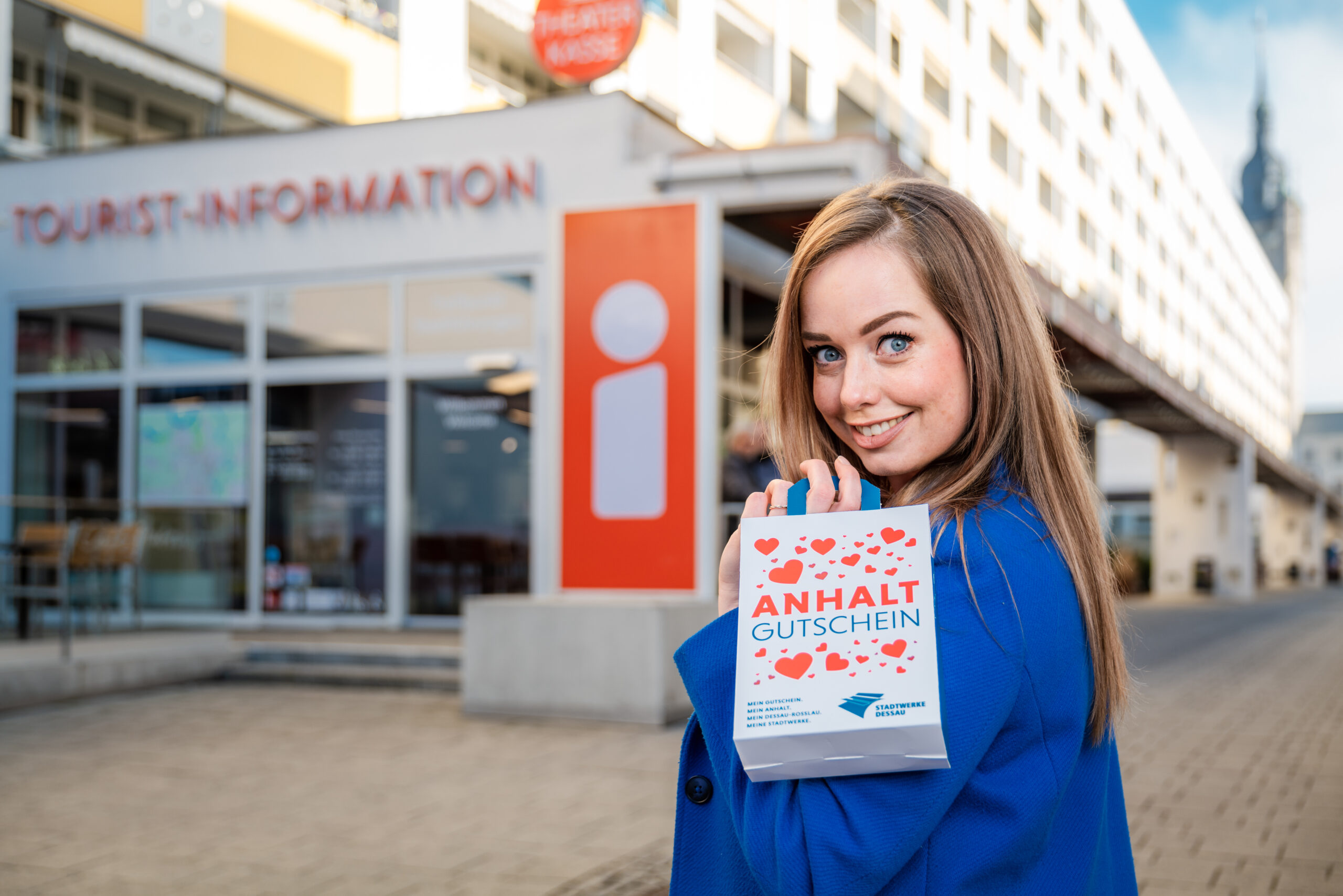 Frau mit einer kleinen Anhalt Gutschein Tüte vor der Touristinfo Dessau