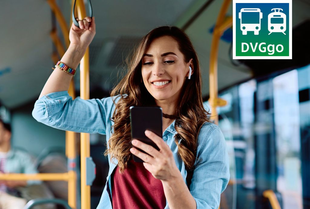 Frau steht mit Handy in der Hand im Bus