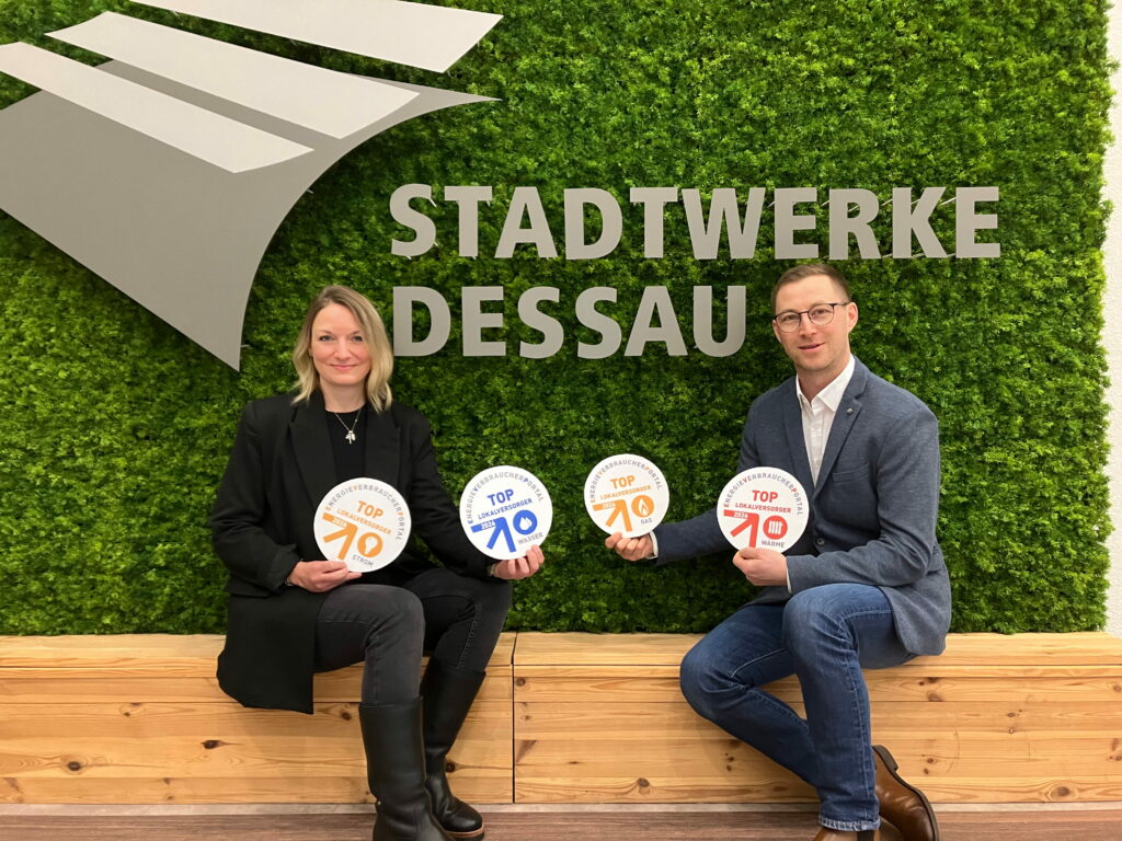 DVV-Mitarbeiter halten Siegel zum Top-Lokalversorger